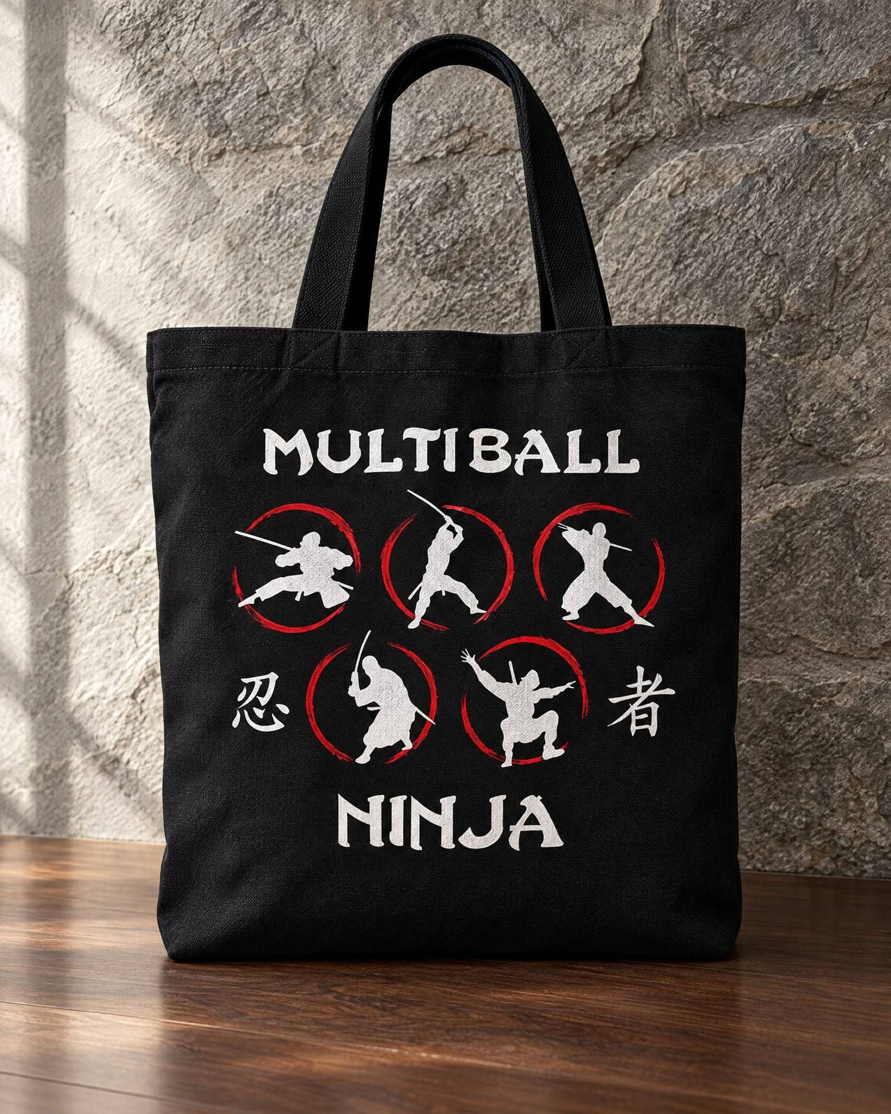 Concept mockup of a black canvas tote printed with the full Multiball Ninja logo, against a stone wall